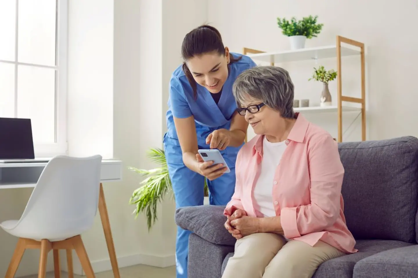 Enfermera enseñando a una anciana a utilizar una aplicación sanitaria móvil