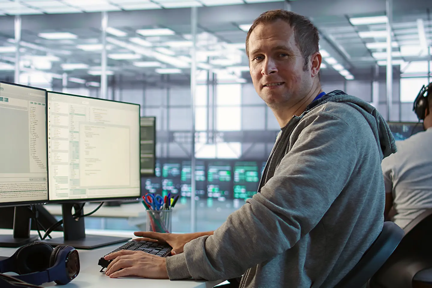 A smiling engineer inspecting server rows in data center