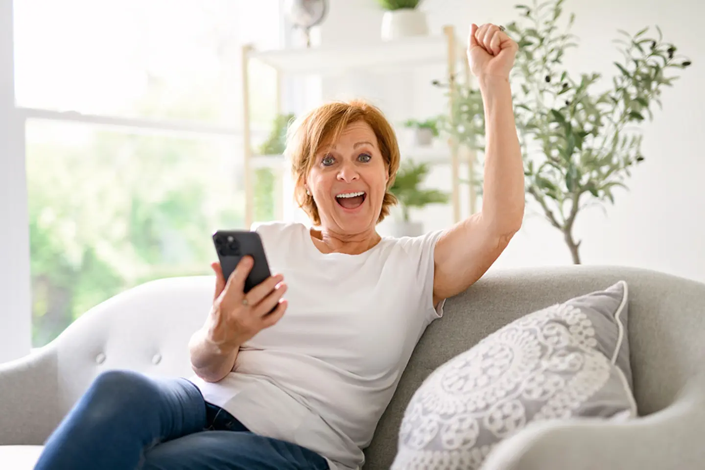 Fröhliche Frau mit Smartphone in der Hand.
