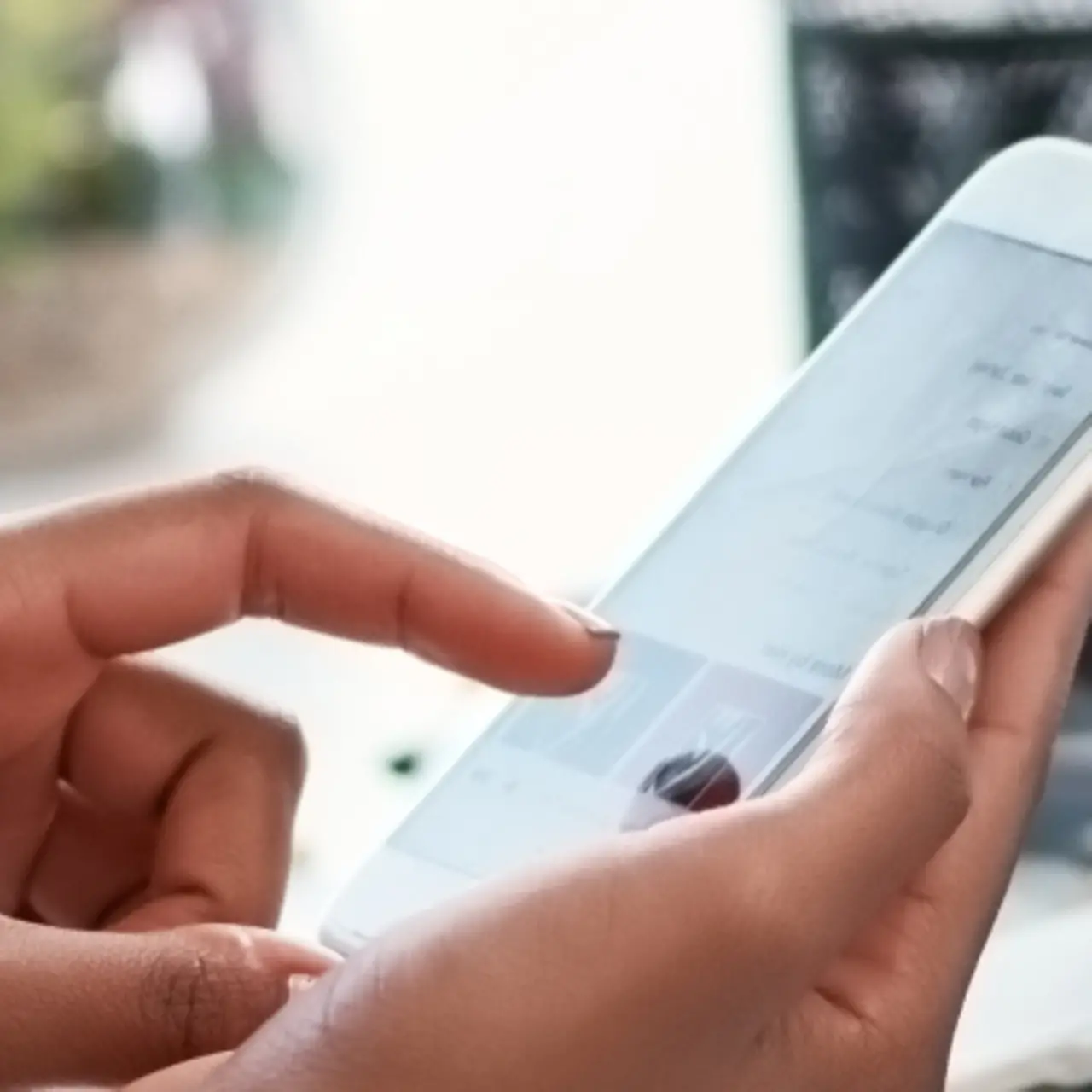Mano con smartphone y laptop con diagramas