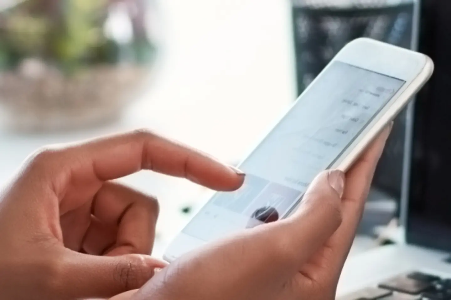 Mano con smartphone y laptop con diagramas