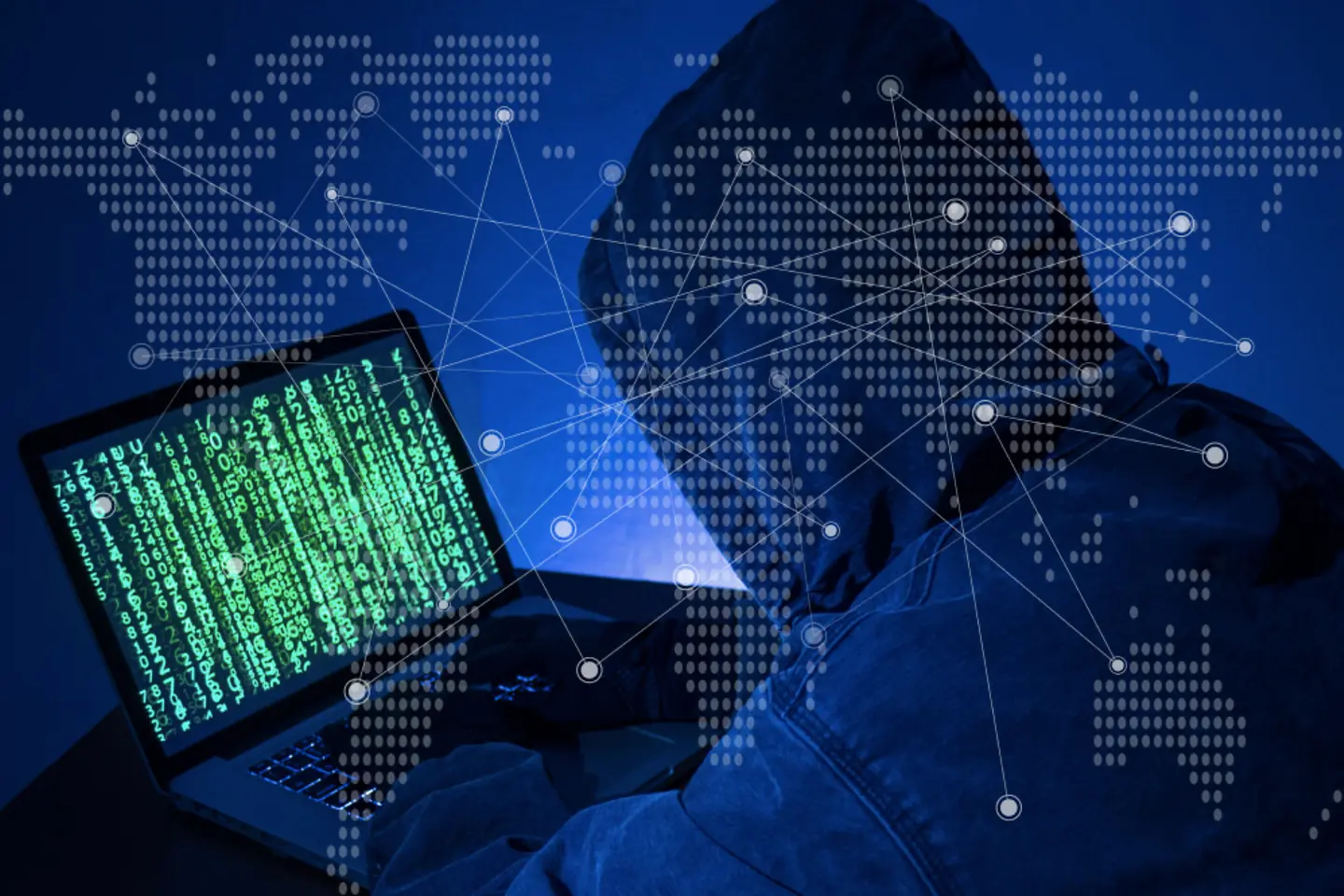 Person with hooded jumper sits in front of a laptop and hacks into the system