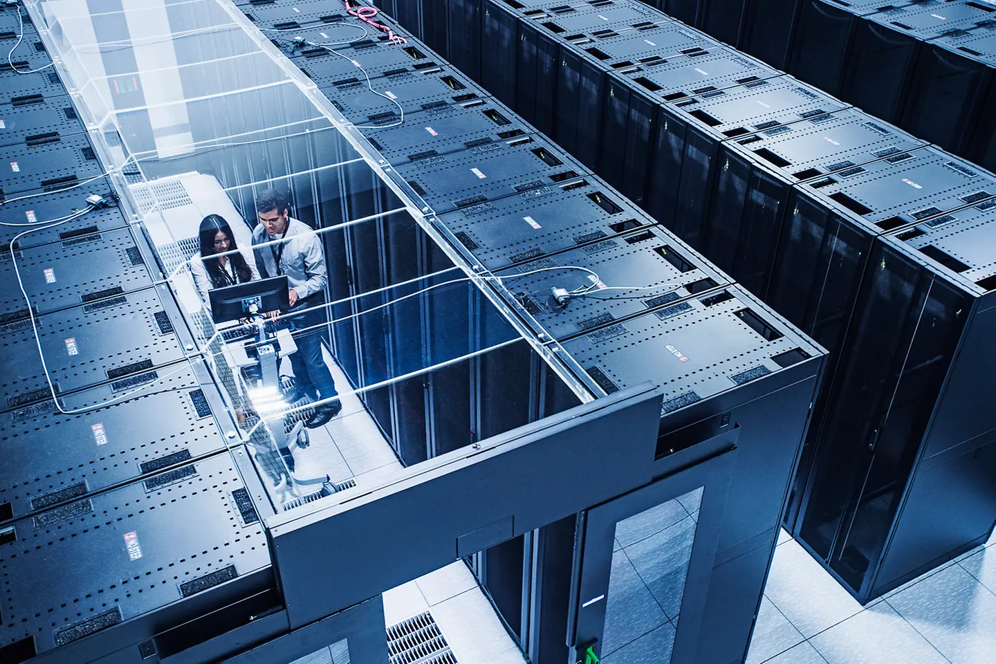 Blick von oben auf Techniker vor einer Reihe von Serverschränken