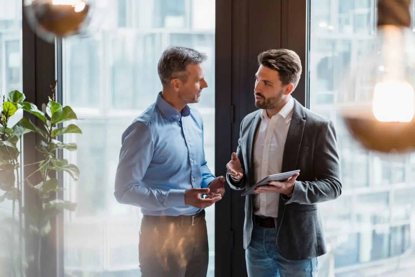 Two men holding an iPad and talking.