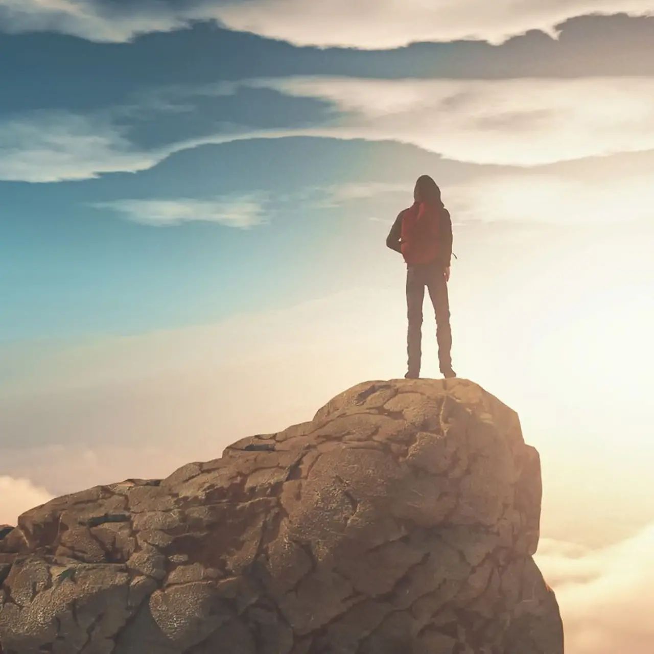 Ein Mann steht auf einem Berggipfel der von Wolken umgeben ist