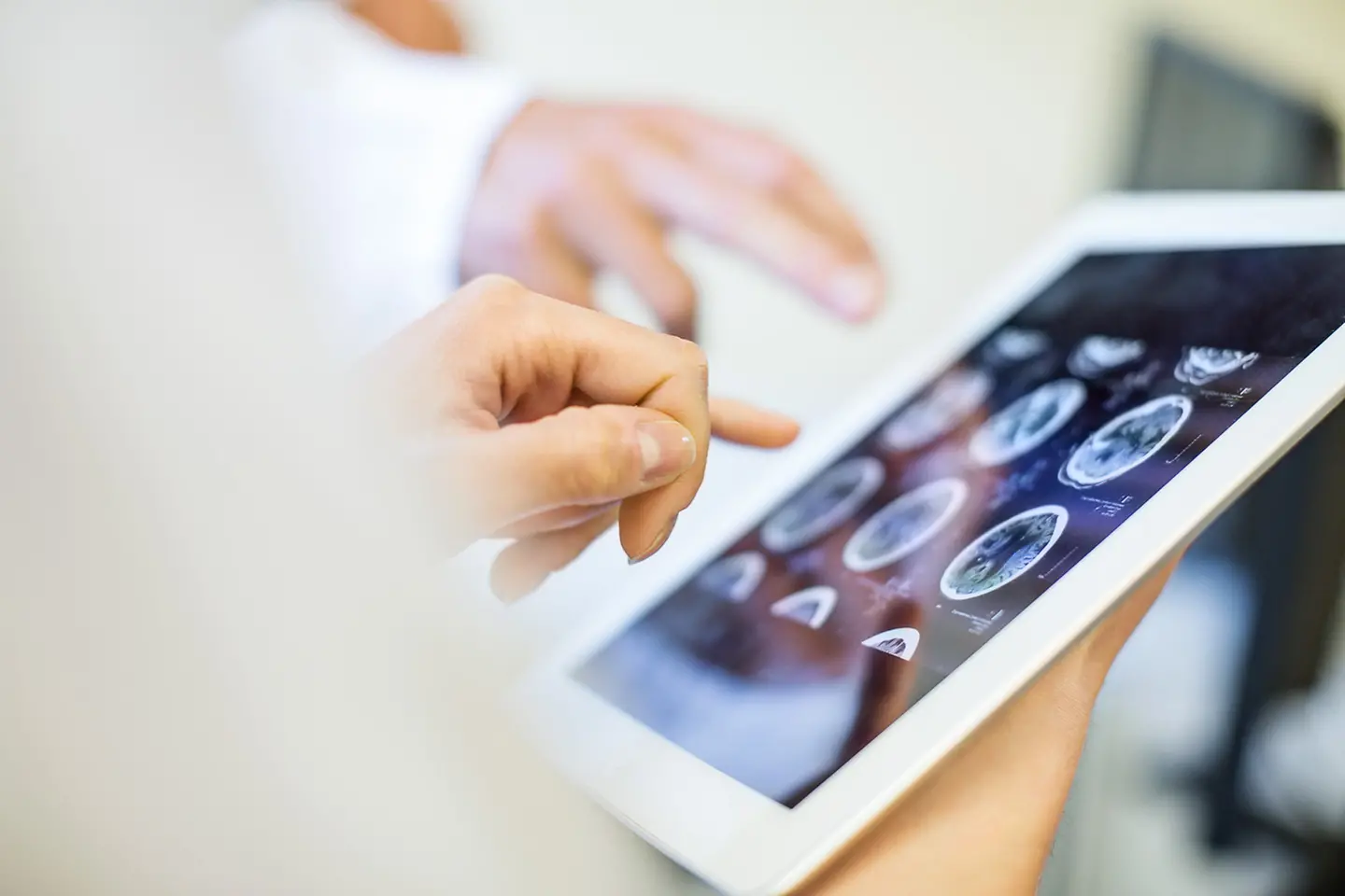 Two doctors evaluate an MRI image on a tablet
